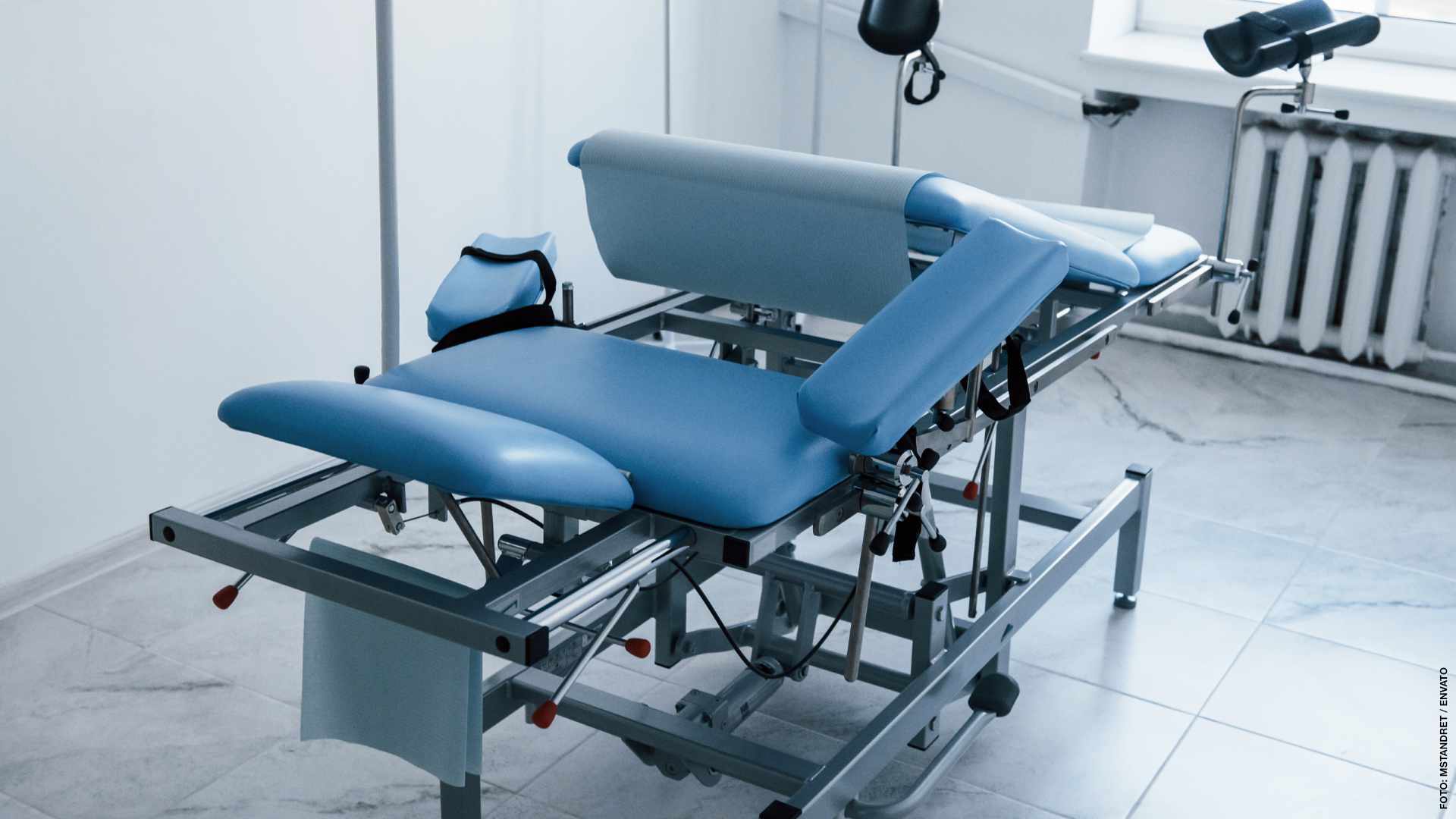 Blue colored obstetric bed indoors in the clinic cabinet at daytime.