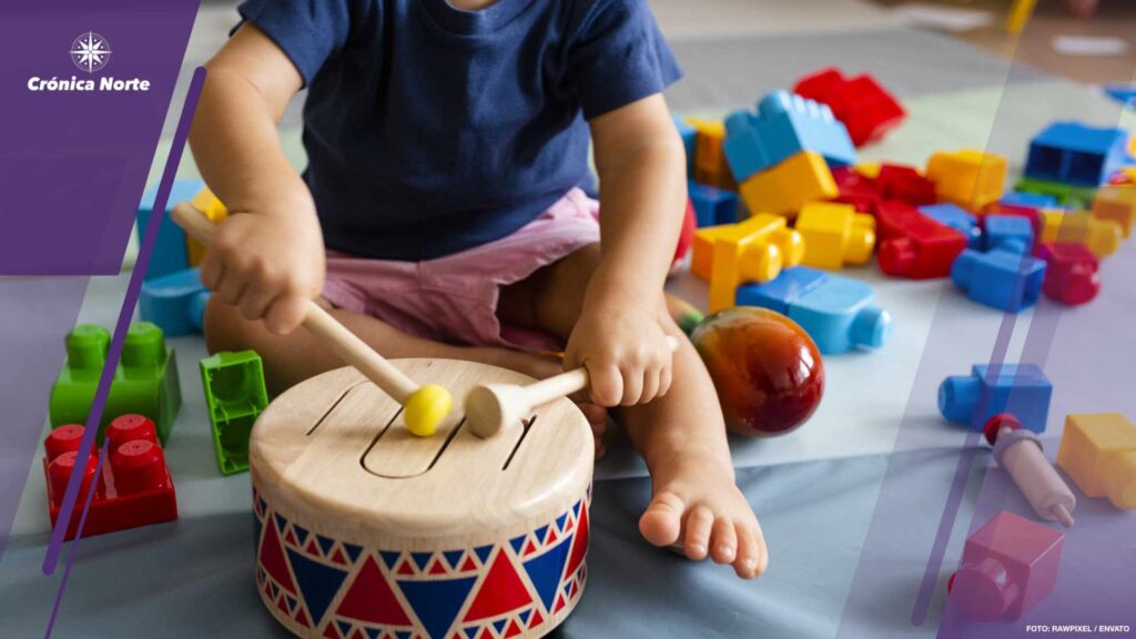 Little boy having fun and playing wooden toy drum